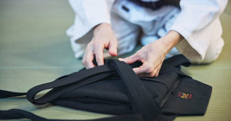 Person, hands and clothing with uniform for martial arts, fashion and aikido gi on floor in dojo....