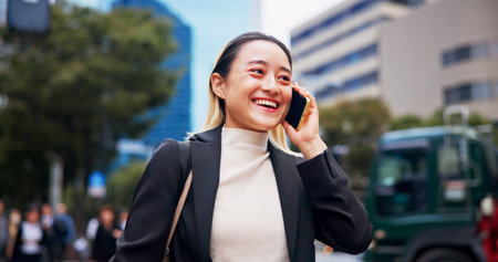 Happy, asian woman and commute with phone call in city for business discussion, conversation or travel. Japan, female person or tourist with smile, talking or mobile smartphone for career opportunityの写真素材