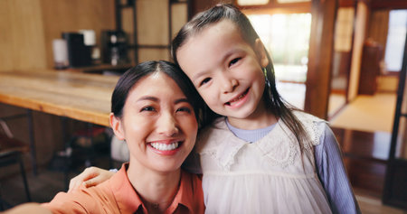 Selfie, hug and mother with child, smile and bonding together with happiness, love and cheerful in home. Japanese family, parent and portrait with girl, embrace and joyful care with comfort in houseの写真素材