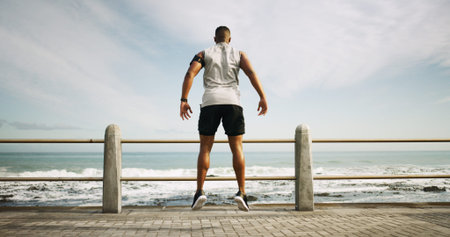 Fitness, beach and back of man with workout, running or marathon training outdoor for speed. Jump,...