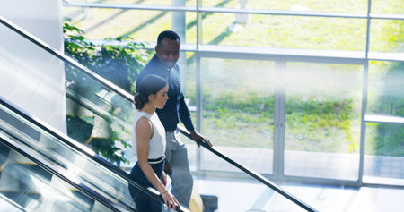 Business, people and talking on escalator in office with project planning, meeting briefing or...