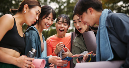 Fitness, people and surprised with phone outdoor for yoga routine video, pilates class announcement and research. Japanese group, smartphone and shocked at park for social media tips or online lessonの写真素材