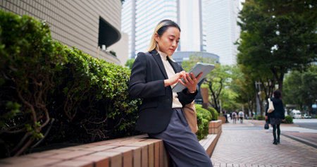 Tablet, city and Japanese woman with job commute, morning and tech of lawyer with email. Online, digital and employee on taxi app for urban travel to work with website, internet and trip in Tokyoの写真素材