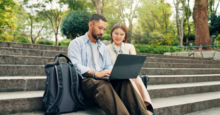 Couple, laptop and reading at park, travel or stairs with search for direction, holiday and...