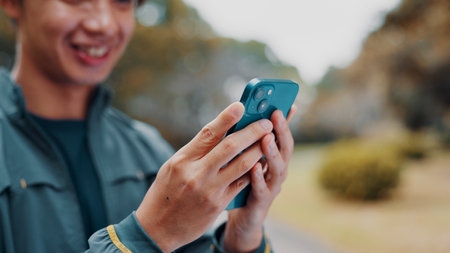 Hands, fitness and smile with phone in park searching for online exercise program for health. Sports, cellphone and athlete person browsing website for workout, routine and outdoor in Japan natureの写真素材