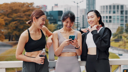 Japan, group and women with smartphone, fitness and typing with funny meme. Connection, outdoor and friends with cellphone, happiness and technology for online reading, digital app and workout goalsの写真素材
