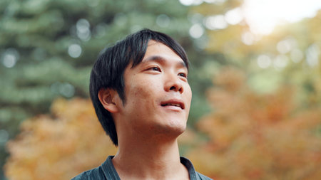 Face, smile and thinking with man in park adventure, conservation or planning of journey or trip. Future, idea and vision with happy Japanese person outdoor in nature for hiking, travel or wellnessの写真素材