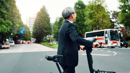Business, man and walking with e bike in city for sustainable transport, eco friendly and carbon neutral travel. Mature person, electric bicycle and morning commute, urban journey and Japan adventureの写真素材