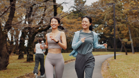 Women, running and bonding for fitness, cardio and training for body goals, wellness or active in morning. Outdoor, smile and workout for Japanese friends, health and together for exercise routineの写真素材