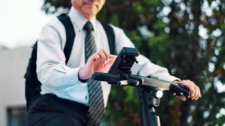 Businessman, phone or hands on electrical bike in city for travel, clean energy or sustainable transport. Commute, ride or eco friendly scooter with mobile app in street for location or map in Japanの写真素材