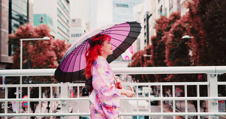 City, umbrella and happy woman in kimono walking on bridge with smile, morning travel or sightseeing. Fashion, pink style and Japanese girl in traditional clothes, parasol or culture on urban commuteの写真素材