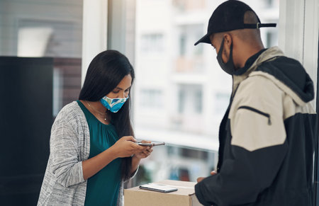 Client, delivery man and face mask with phone of courier service, mobile payment and distribution compliance. People, package or online shopping of digital transaction, commerce safety and front doorの写真素材