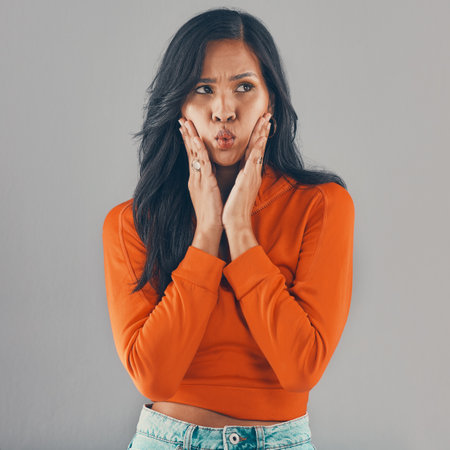 Studio, pout and woman with confused face, doubt and thinking of skincare ideas for wellness. Sad, frustrated and gen z girl with funny facial gesture for beauty, identity or skin on grey backgroundの写真素材