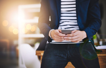 Phone, hands and business man online, typing email or bokeh with flare in creative startup. Mobile, worker and chat app for communication, brand promo and media strategist check campaign progressの写真素材