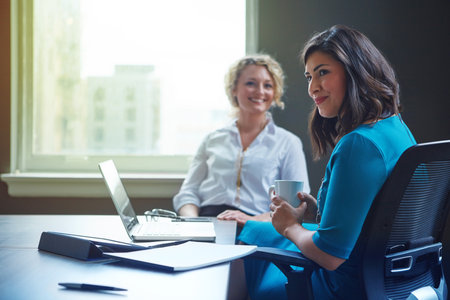 Laptop, documents and women in office together for collaboration, development or business plan. Partnership, finance and project management team in meeting for online budget proposal, report or salesの写真素材