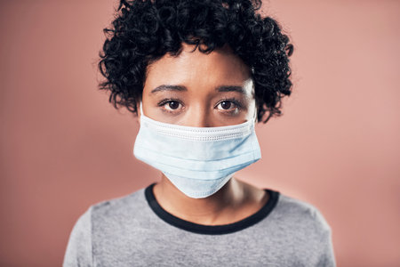 Studio, portrait and woman with face mask for safety, health compliance and protection for virus. Female person, sick and awareness with cover for fever disease, wellness crisis and pink backgroundの写真素材