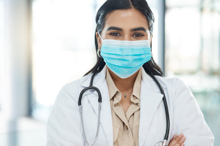 Portrait, girl and doctor with face mask in hospital of healthcare services, ppe safety and medical compliance. Woman, surgeon and arms crossed for virus danger, wellness risk and about us of surgeryの写真素材