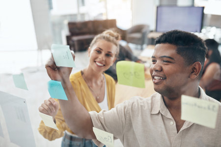 Office, teamwork and business people with sticky notes for brainstorming, planning and solution ideas. Glass wall, collaboration and employees with writing for problem solving, schedule and startupの写真素材