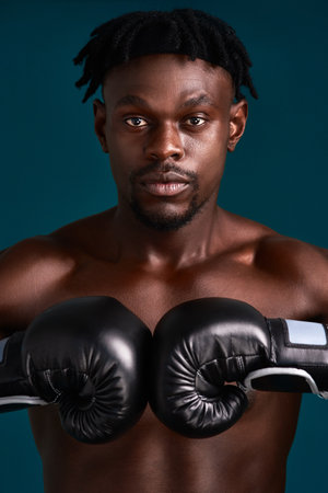 Studio, black man and portrait with gloves for boxer, mma workout and prepare for fight competition. Fitness, male person and boxing with training for fist, resilience or challenge by dark backgroundの写真素材
