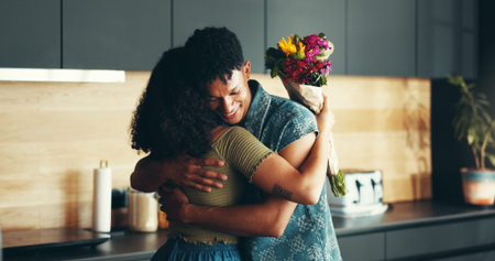 Love, couple and hug with flowers in kitchen for valentines day, romance and celebration of marriage. Gratitude, people and thank you for floral bouquet with support, commitment and surprise giftの写真素材