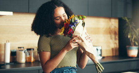 Happy woman, flowers and aroma as romantic gift or gesture for anniversary, birthday or celebration. Female person, bouquet and smelling with joy, smile and love in home as present for valentines dayの写真素材