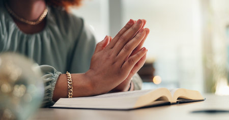 Hands, prayer and bible for faith in home with worship, peace or study for spiritual guide. Person, Christian book and religion for reflection, scripture or search for connection to God at apartmentの写真素材