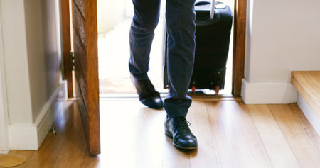 Front door, person and luggage in home from travel, feet and return from international business trip. Shoes, legs and suitcase for baggage, enter and arrival at house from global flight in morningの写真素材