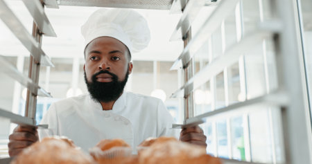 Muffin, bakery and cafe with man in kitchen for coffee shop, food industry and breakfast. Shelf, chef and nutritionist with male baker and dessert trolley in restaurant for baking, hotel and orderの写真素材