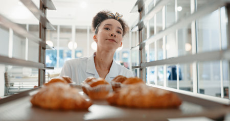 Croissant, bakery and pastry with woman in kitchen for coffee shop, food industry and breakfast. Shelf, chef and nutritionist with baker and dessert trolley in restaurant for baking, hotel and cafeの写真素材