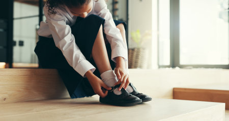 Hands, child and tie shoes for school as morning routine, getting ready in home or preparation for education. Feet, uniform and girl student with start to day for learning, dressing or footwearの写真素材