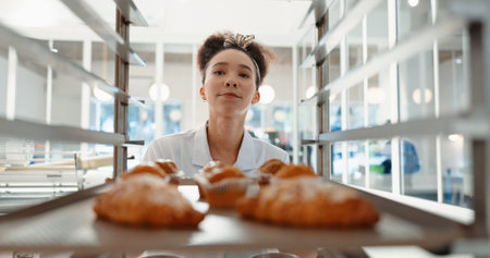 Croissant, bakery and cafe with woman in kitchen for coffee shop, food industry and breakfast. Shelf, chef and nutritionist with baker and dessert trolley in restaurant for baking, hotel and pastryの写真素材