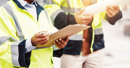 People, clipboard or hands with architect for construction checklist, inspection or planning in city. Closeup, civil engineer or contractors with document for building layout, project or safety checkの写真素材