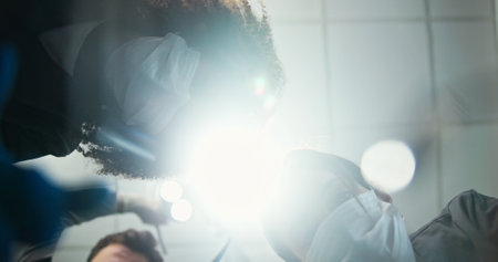 Dentist, team or light below with dental team for hygiene, cleaning or cavity removal at hospital. Lens flare, low angle and medical orthodontist with patient checkup for oral, mouth or gum care examの写真素材