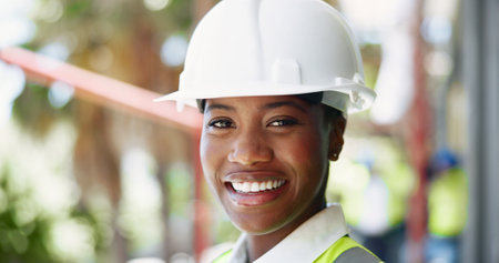 Portrait, black woman and happy architect with helmet at construction site for safety or renovation. Face, smile and professional civil engineer by building, working or maintenance outdoor in Ghanaの写真素材