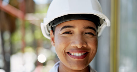 Portrait, happy woman and architect with helmet at construction site for safety or renovation project. Face, smile and professional civil engineer by building, working or maintenance outdoor in Indiaの写真素材