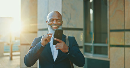 Cellphone, travel and businessman in city with communication, social networking or connectivity online. Happy, phone and African male lawyer with email for legal case information on commute in town.の写真素材