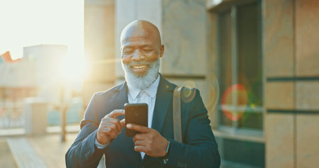 Black man, city lawyer and phone for commute, agenda and online for consulting on legal case. Male person, urban town and travel to office building for justice, counsel client and message on appの写真素材