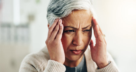 House, stress and senior woman with headache, burnout and tension with pain. Pensioner, anxiety or elderly person with migraine, retirement or aged with burnout, frustrated or fail with mental healthの写真素材