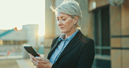 Phone, travel and businesswoman in city with communication, social networking or connectivity. Online, cellphone and mature female lawyer with email for legal case information on commute in town.の写真素材