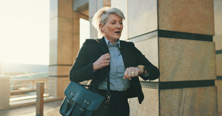 Late, running and business woman with watch in city for urgent meeting, rushing to appointment or panic. Mature professional, hurry and schedule mistake for morning commute or time management outdoorの写真素材