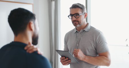 Physiotherapy, tablet and shoulder pain with man and athlete in clinic for rehabilitation, healthcare or consulting. Support, medical and chiropractor with people for healing, advice or injuryの写真素材