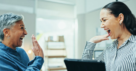 Women, happy or high five with tablet for business, startup partnership or achievement in office. Excited people, tech or gesture in company for collaboration, positive feedback or bank loan approvalの写真素材