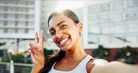 Fitness, portrait and woman with selfie, peace sign and workout or exercise for training break on social media. Happy influencer, runner and girl in profile picture for online post or vlog in cityの写真素材