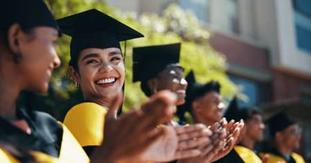 People, students and applause at university for graduation, peer support and happy for achievement. Class, clapping and outdoor on campus for academic success, pride and smile for education milestoneの写真素材