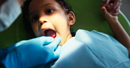 Dentist, consulting and above of child in clinic for toothache, tooth extraction and wellness. Healthcare, dentistry and patient with hygienist for dental hygiene, oral care and medical servicesの写真素材