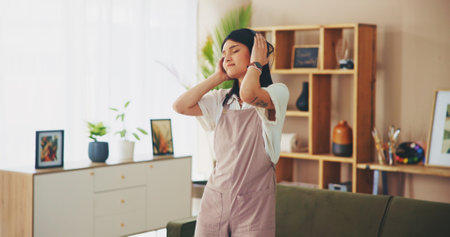 Girl, dancing and listening to music in living room, relax and eyes closed with subscription in home. Woman, person and dancer with streaming services for audio, tech and rhythm with sound at houseの写真素材