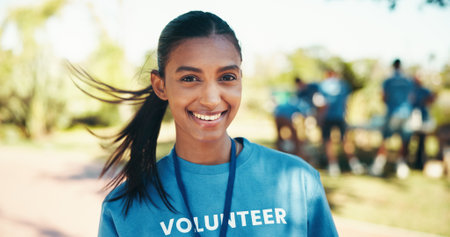 Charity, portrait and wind with woman volunteer outdoor in park for community food drive or donation. Activism, smile and society development with happy person as welfare worker for NGO or non profitの写真素材
