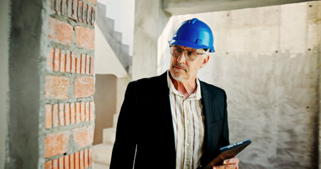 Construction site, thinking and man with tablet, inspection and network with online schedule. Mature person, architecture and employee with hard hat, technology and solution with quality controlの写真素材
