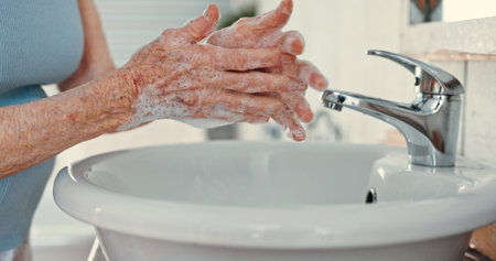 Hygiene, senior woman and washing hands in bathroom for bacteria removal, skincare and germ prevention. Elderly, person and cleaning dirt by basin for skin safety, wellness routine and disinfectionの写真素材