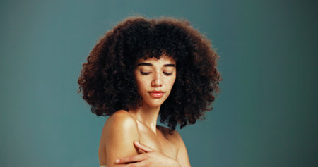 Beauty, glow and woman with afro hair care, studio and treatment for wellness and health. Face, shoulder or confident girl model with skin, growth and natural texture on green background in Brazilの写真素材